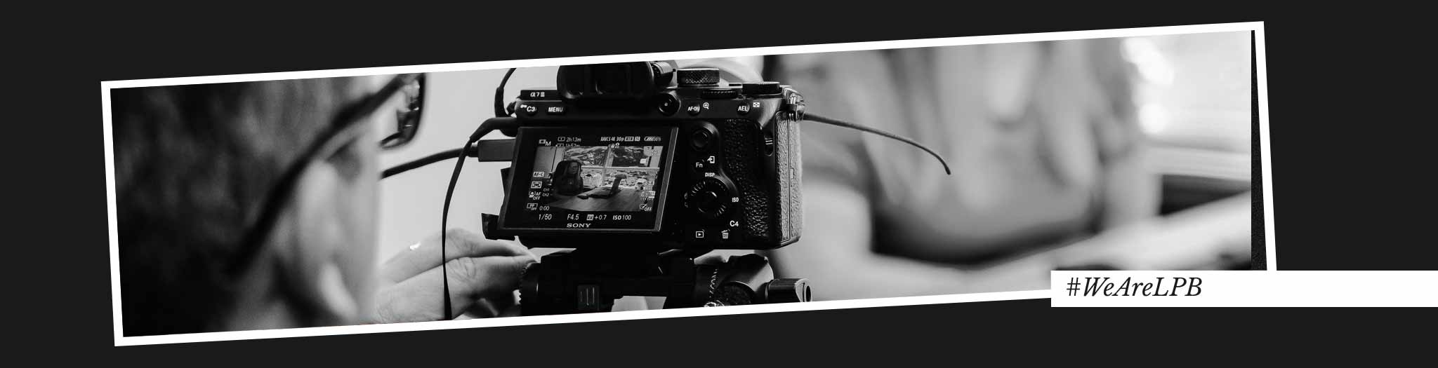 Portada de blog videos corporativos para empresas con un cámara grabando a una mujer en su despacho. Se ve la mujer a través de la pantalla de previsualización.